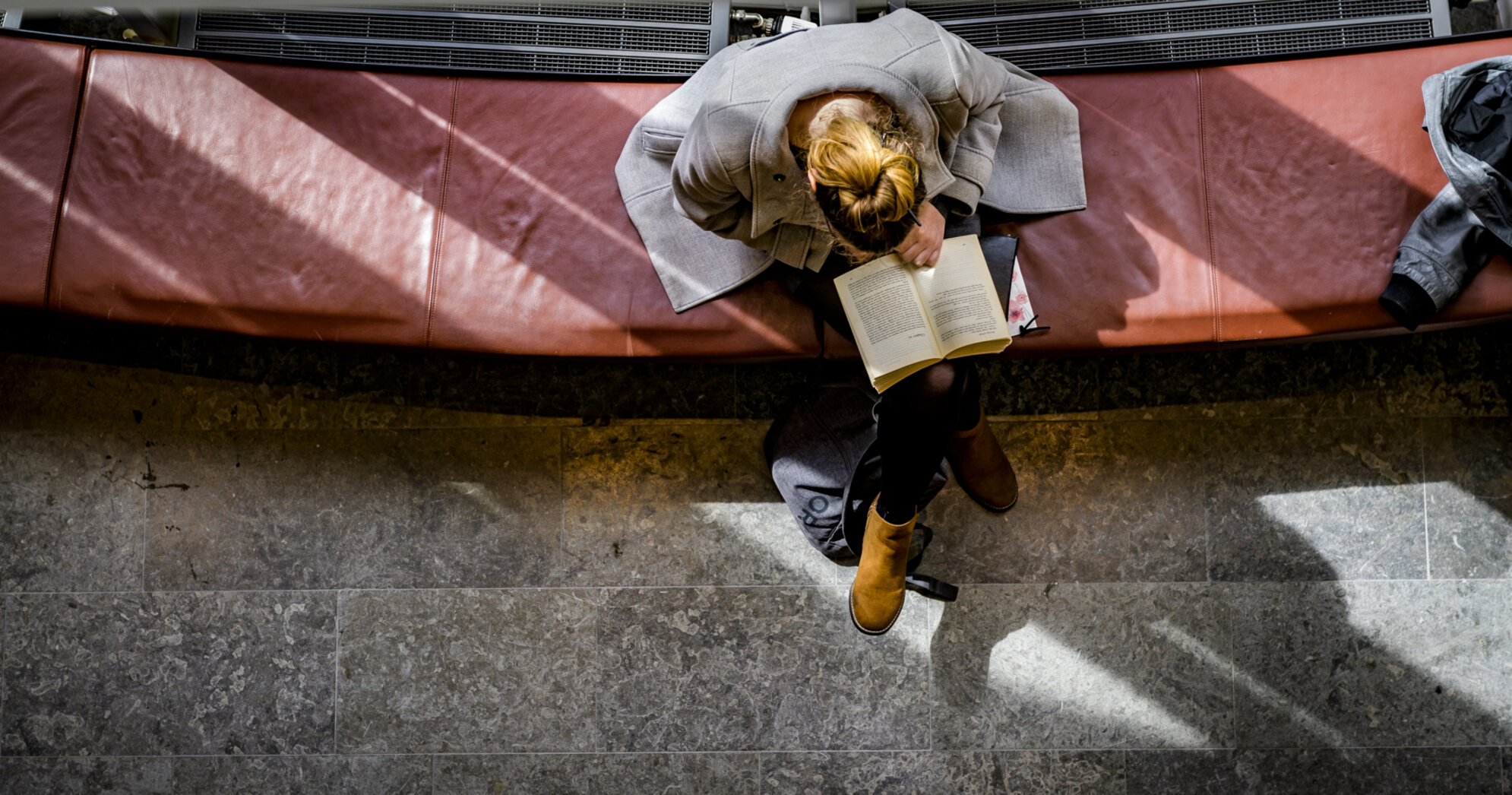 Student läser bok på soffa